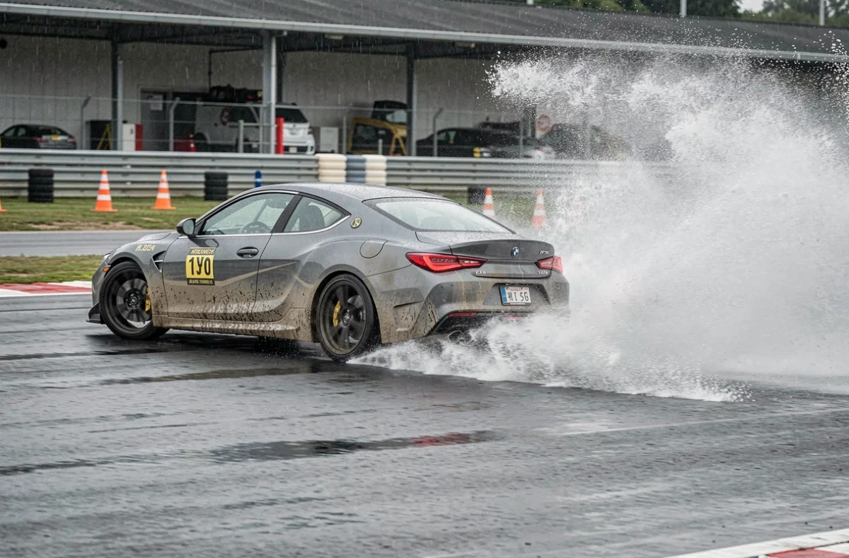 Voiture de sport en dérapage contrôlé sur circuit mouillé pendant un stage de pilotage sous la pluie avec gerbe d'eau